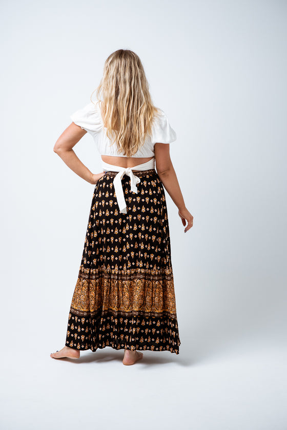 Beautiful and easy wearing, the Nina Maxi Skirt is available in a Black and Tan boho border print on super soft rayon. Featuring an ankle length skirt with elastic waistband, tie & tassel trim and a single tiered gather hem and front split. Perfect to style with a print tee for a simple but striking day look. Available from www.arlowboutique.com