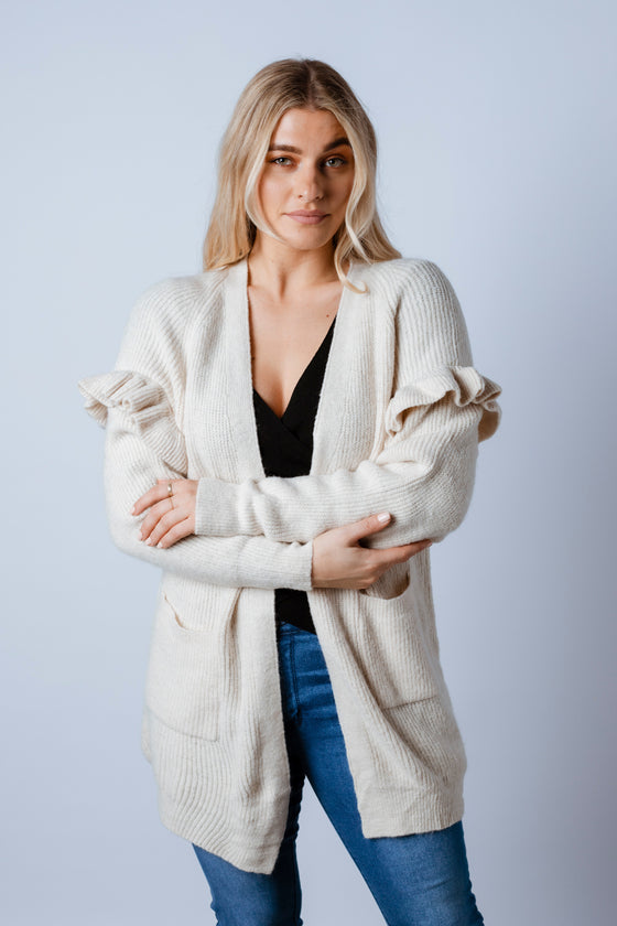 Soft and femme. The Essie Knit Cardigan features a gorgeous cream colour, a soft knit yarn with off shoulder frill detailing, front pockets and a mid thigh body length. Available from arlowboutique.com.au